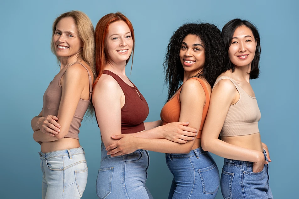 Diverse group of smiling, confident women in crop tops, representing natural breast variations.